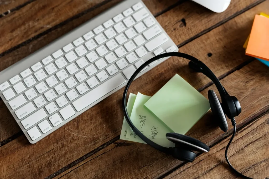 IMagen de un escritorio con un teclado, auriculares y block de notas
